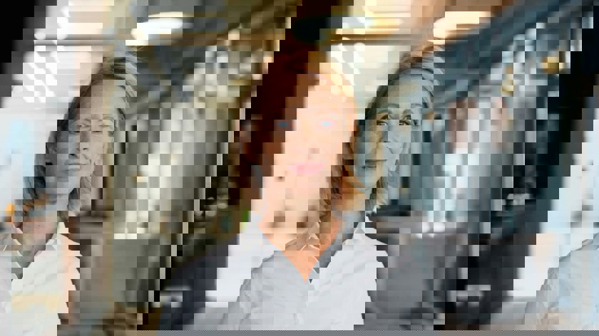 Foto av kvinna i vit skjorta tittar in i kameran.