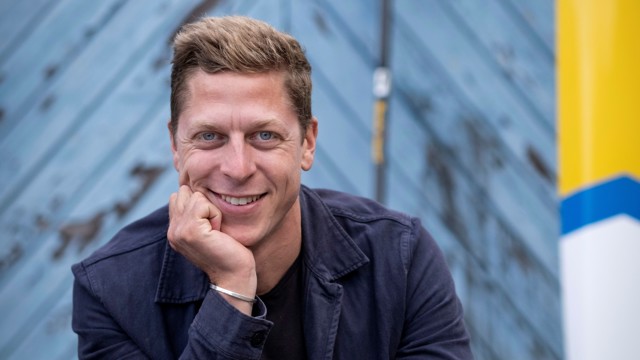 Porträttbild av Petter Menning, leende med blicken in i kameran. Blå bakgrund.